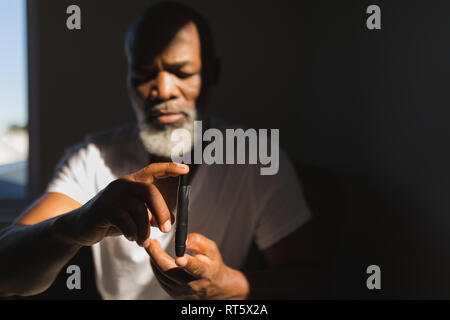 Älterer Mann mit glucometer Kontrolle der Blutzuckerspiegel zu Hause Stockfoto