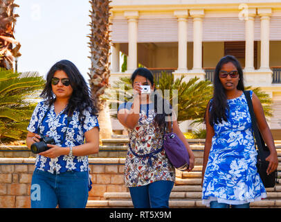 Ein Trio der intelligente, selbstbewusste, schönen indischen Frauen mit floralen Tops, die Kameras und Bilder aufnehmen, und zu Fuß die Treppe hinunter. Stockfoto