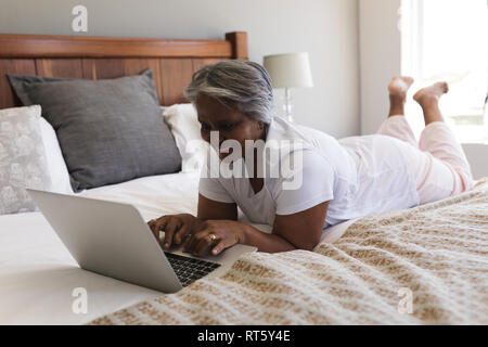 Ältere Frau mit Laptop im Schlafzimmer zu Hause Stockfoto