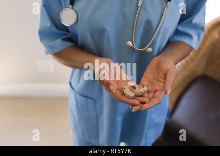 Ärztin holding Hörgerät Maschine zu Hause Stockfoto