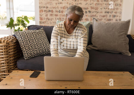 Ältere Frau mit Laptop im Wohnzimmer Stockfoto