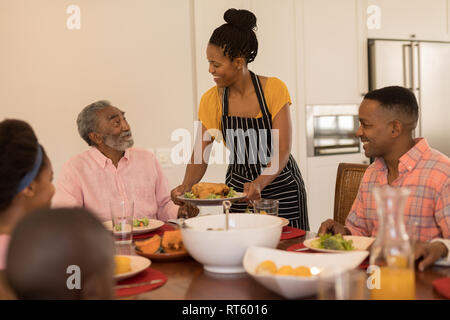 Frau das Essen zu ihrer Familie am Esstisch Stockfoto