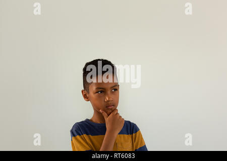 Junge mit der Hand am Kinn vor weißem Hintergrund Stockfoto