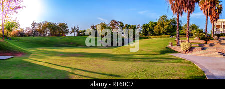 Eine versunkene grüne Rasen an The Golkonda Resorts und Spa in Hyderabad, Telangana, Indien. Bäume werfen einen langen Schatten in der Abendsonne. Stockfoto