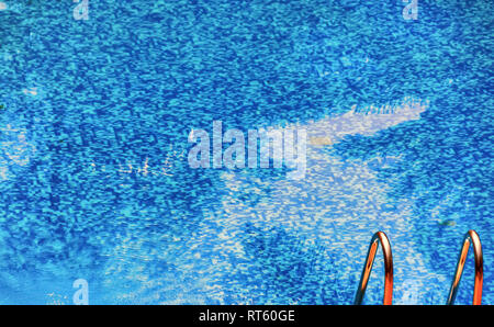 Der Handlauf der Treppe in einem leeren Swimmingpool. Kleine Bläschen und Wellen sind sichtbar, als das Wasser wird langsam mit einem Luftkompressor entlüftet ist. Stockfoto