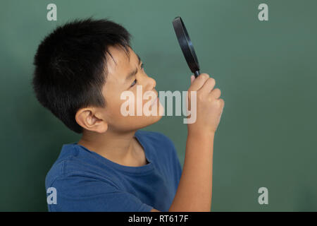 Schüler durch die Lupe gegen greenboard in einem Klassenzimmer Stockfoto