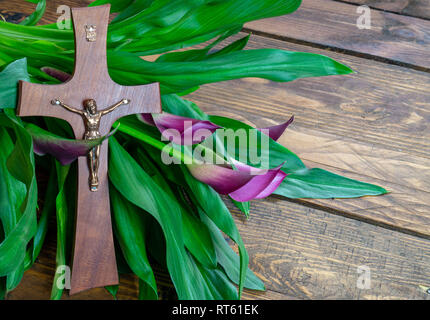 Kreuz mit Jesus Christus auf einem hölzernen Hintergrund mit einem violetten Calla-religiösen Ostern Fastenzeit Konzept Hintergrund Stockfoto