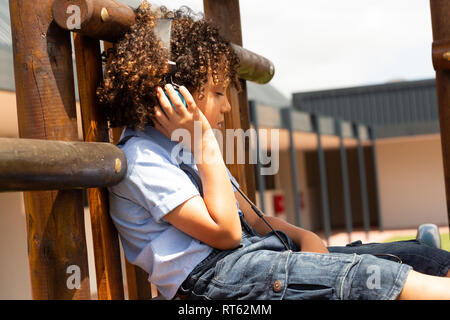 Schülerin Musik hören über Kopfhörer in der Schule Spielplatz Stockfoto