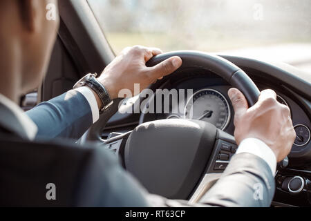 Junge Unternehmer Fahrer tragen watch Sitzen im Auto mit Lenkrad fahren Nahaufnahme Rückansicht Stockfoto