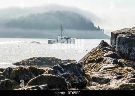 Ein Lobster Boat Position von Bar Harbor Maine mit porcupine Insel im Nebel im Hintergrund auf einem August morgens bedeckt. Stockfoto