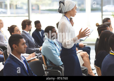 Junge Geschäftsfrau Fragen stellen während des Seminars Stockfoto