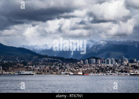 North Vancouver City Skyline mit schneebedeckten Gipfeln hinter, Blick vom Stanley Park waterfront Pfad über den Hafen, Vancouver, Kanada Stockfoto