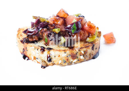Frisches Bruschetta mit einer Vielzahl von Oliven und würfelt Tomaten auf kleinen getoasteten Brotscheiben Balsamico beträufelt mit einer Ermäßigung auf eine whit isoliert gemacht Stockfoto