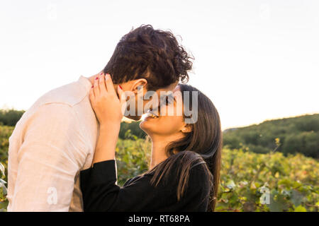 Italien, Toskana, Siena, glückliches junges Paar Küssen in einem Weinberg Stockfoto