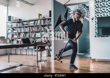 Mann mit indischen Kopfschmuck und VR-Brille in Büros über Kick scooter Stockfoto