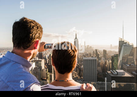 USA, New York City, Mann mit Frau, Handy Bild auf dem Rockefeller Center Aussichtsplattform Stockfoto