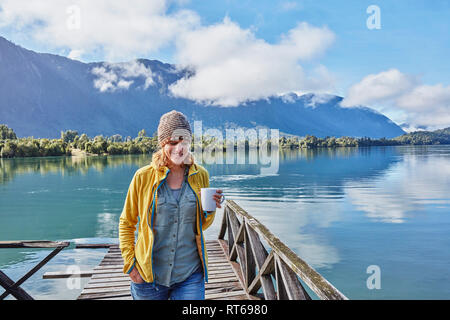 Chile Chaiten, Lago Rosselot, Frau gehen auf Jetty holding Becher Stockfoto