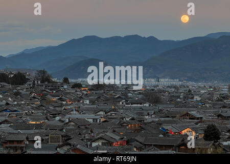 Dächer in Lijiang Altstadt und aufgehenden Mond im Hintergrund, Yunnan Stockfoto