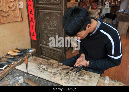 Shaxi, China - 21. Februar 2019: Chinesische Künstler Carving eine Holzplatte in Shaxi Altstadt Stockfoto