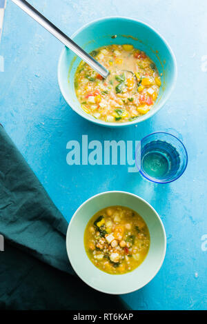 Typische italienische Minestrone, eine gesunde Suppe von Bohnen und Gemüse, oben viiew, flatlay über einem blauen Board Stockfoto