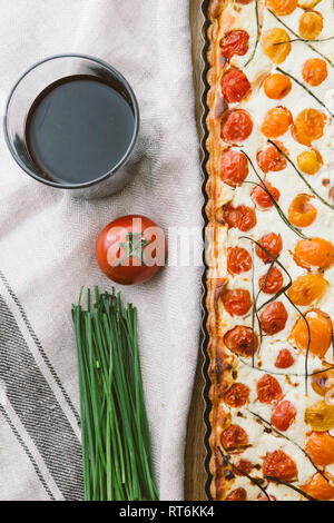 Hausgemachte Kuchen (quiche) mit Ricotta, frischen farbigen Tomaten, rechteckige Formen auf einem cutboard, Ansicht von oben, mit Schnittlauch, ein Glas Wein und Tomaten, Weiß Stockfoto