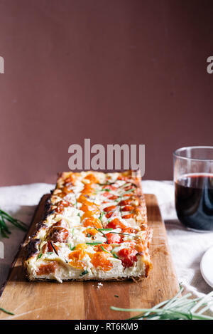 Hausgemachte Kuchen (quiche) mit Ricotta, frischen farbigen Tomaten, rechteckige Formen auf einem cutboard, frontal, Holz- rustikalen Hintergrund Stockfoto