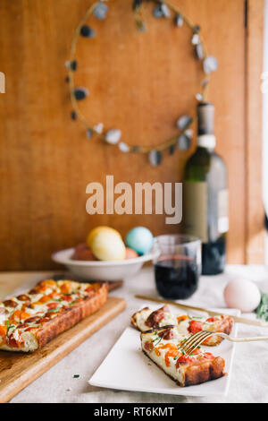 Hausgemachte Kuchen (quiche), mit Ricotta und frischen farbigen Tomaten, in Scheiben schneiden, in eine Schüssel mit goldenen Gabel schneiden, ein Glas Wein, rechteckigen Formen, frontal Stockfoto