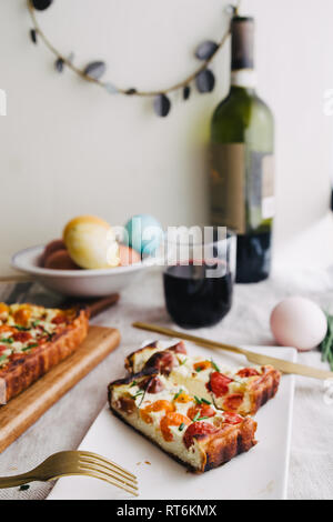 Hausgemachte Kuchen (quiche), mit Ricotta und frischen farbigen Tomaten, in Scheiben schneiden, in eine Schüssel mit goldenen Gabel schneiden, ein Glas Wein, rechteckigen Formen, frontal Stockfoto