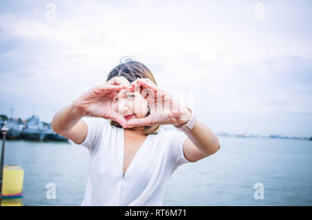 Schöne glückliche Frau mit Herzförmigen Hände. Stockfoto