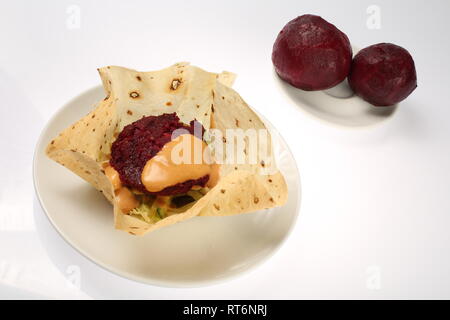 Vegetarische Burger in Mais Tortillas mit Rote Bete, Karotten, Zwiebeln, Kohl und grünem Salat, Kichererbsen und Avocados auf einem Teller, auf weißem Hintergrund Stockfoto