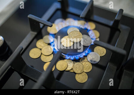 Kosten für Gas, Konzept Krise. Gasherd mit Münzen in der Flamme. Die Kosten von Methan. Gas Münzen teurer Stockfoto