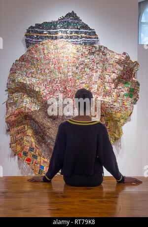 Oktober Gallery, London, Großbritannien. 28. Februar, 2019. El Anatsui: Material Wunder verfügt über die ghanaische Bildhauer unverwechselbare große und komplexe Metall wand Skulpturen von Assemblagen aus Aluminium Flasche Oberseiten von Alkohol Recycling Stationen gemacht zusammen mit Kupferdraht genäht. Bild: Galerie Personal mit Iris, 2012. Credit: Malcolm Park/Alamy Leben Nachrichten. Stockfoto