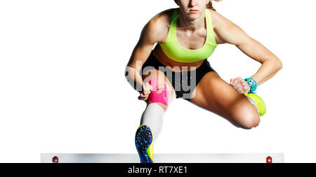 Junge Athletin über Hürde im Sprint springen. Sprinter über Hindernis auf weißem Hintergrund springen Stockfoto