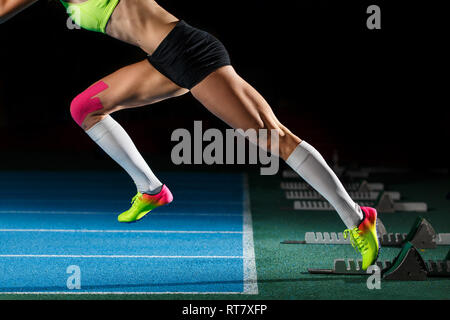 Weibliche Athleten starten Sprint Rennen laufen von Blöcken auf schwarzem Hintergrund Stockfoto