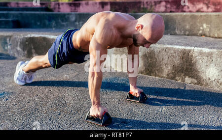 Barechested muskulösen Mann tun Push-ups im Freien Stockfoto