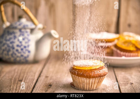 Besprengung Puderzucker auf Muffin mit kandierten Orangen auf der Oberseite Stockfoto