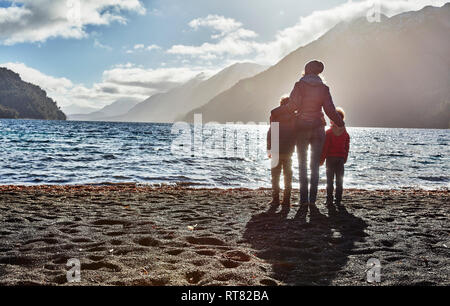 Argentinien, Patagonien, Lago Nahuel Huapi, Frau mit zwei Söhne stehen am Ufer mit Blick auf den See Stockfoto