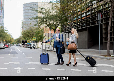 Senior Geschäftsmann und Geschäftsfrau mit Gepäck über die Straße in der Stadt Stockfoto