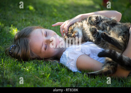 Mädchen liegt mit Katze im Garten Stockfoto