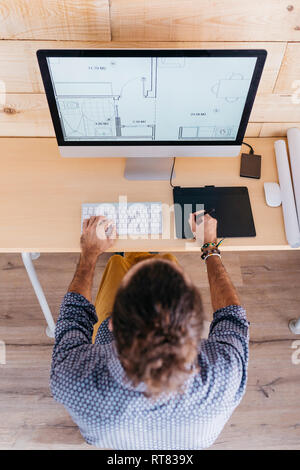 Blick von oben auf die jungen Mann auf Grundriss zu Hause arbeiten mit dem Computer Stockfoto