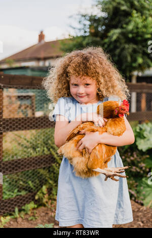 Lächelnde Mädchen umarmt Henne Stockfoto