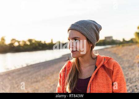 Porträt einer sportliche junge Frau am Fluss, weraing eine Beanie-mütze Stockfoto