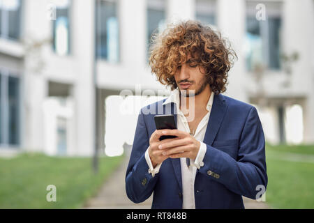 Junge Unternehmer mit lockigem Haar Text Messaging Stockfoto