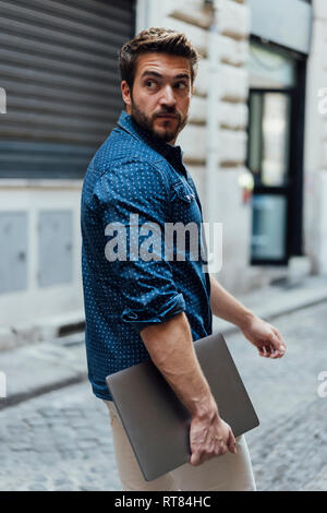 Portrait von Geschäftsmann mit Laptop auf der Straße beobachten etwas Stockfoto