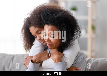 Liebevolle Mutter und Tochter mit geschlossenen Augen umarmt Stockfoto