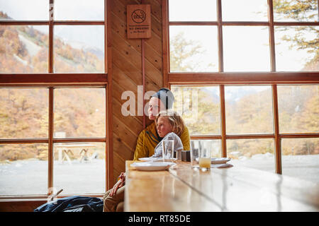 Chile, Torres del Paine Nationalpark, Mutter mit Sohn sitzen am Tisch in einer Berghütte Stockfoto