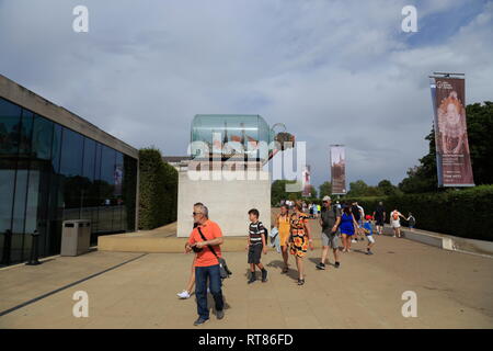 Menschen gehen vorbei an einer Replik von Lord Nelson HMS Victory Schiff in einer Flasche, außerhalb der Sammy Ofer Flügel Museum in Greenwich, London, Vereinigtes Königreich. Stockfoto