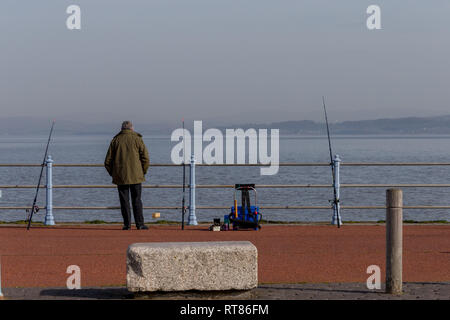 Ein einsamer See angler angeln von der steinernen Pier auf der Morecambe Bay Stockfoto