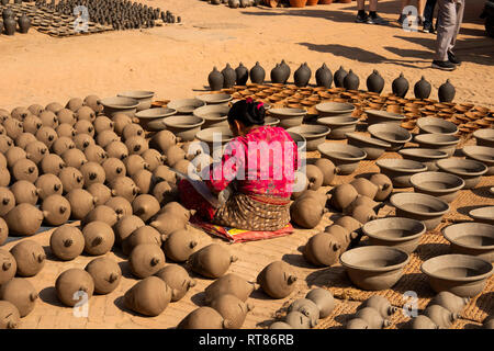 Nepal, Kathmandu Tal, Bhaktapur, Potter's Square, Frau schlichten thown Töpfe trocknen in der Sonne vor dem Feuern im Brennofen Stockfoto