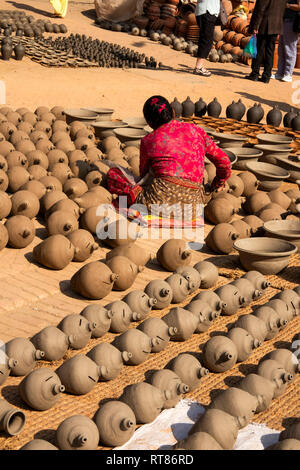 Nepal, Kathmandu Tal, Bhaktapur, Potter's Square, Frau schlichten thown Töpfe trocknen in der Sonne vor dem Feuern im Brennofen Stockfoto